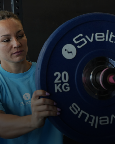 Une femme rangeant un disque olympique compétition sur une barre olympique