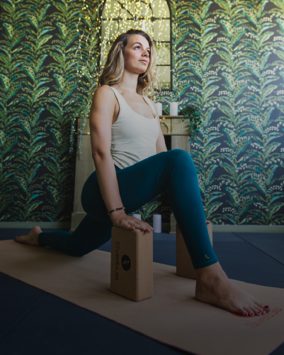 Une femme réalisant des poses de Yoga sur un tapis de Yoga avec une brique en lièce
